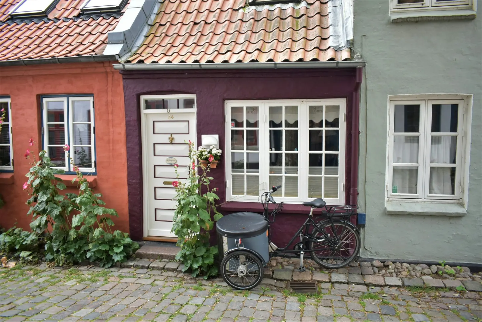Rødt byhus med cykel foran vinduerne