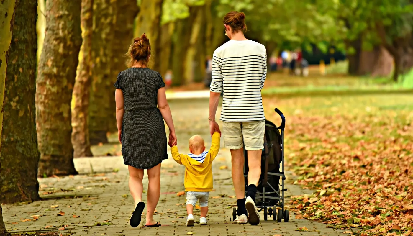 Familie med barnevogn går en tur i en park