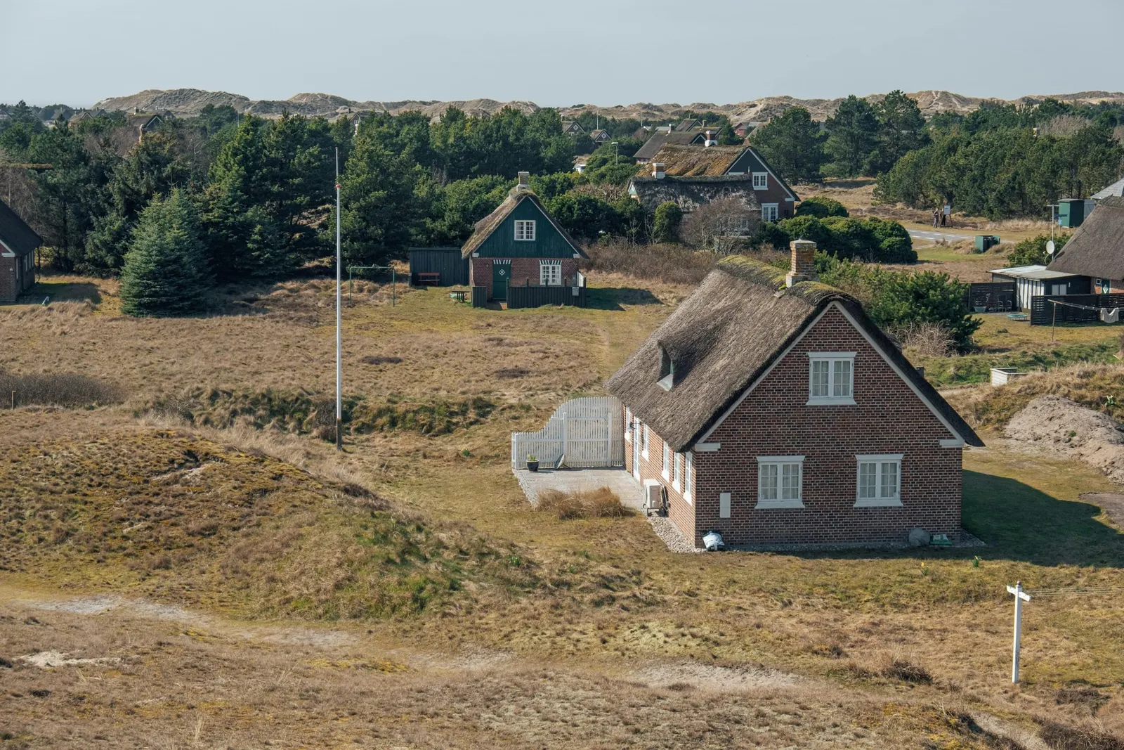 Stråtækt sommerhus i et klitlandskab