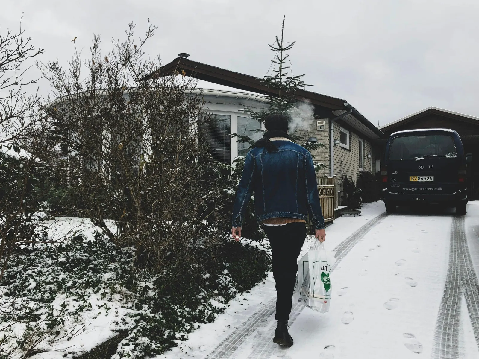 Person går mod et hus ad en snedækket indkørsel