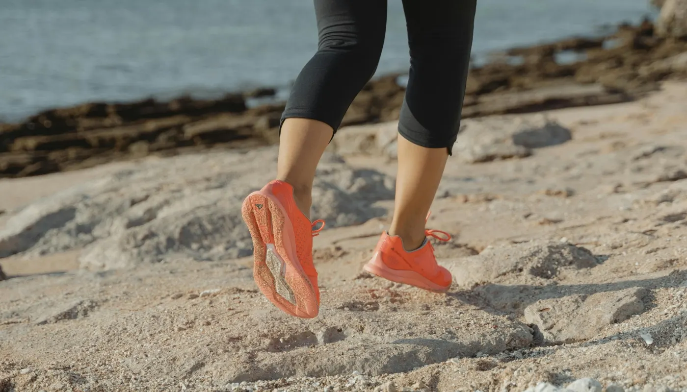 Løber med orange løbesko på en sandstrand